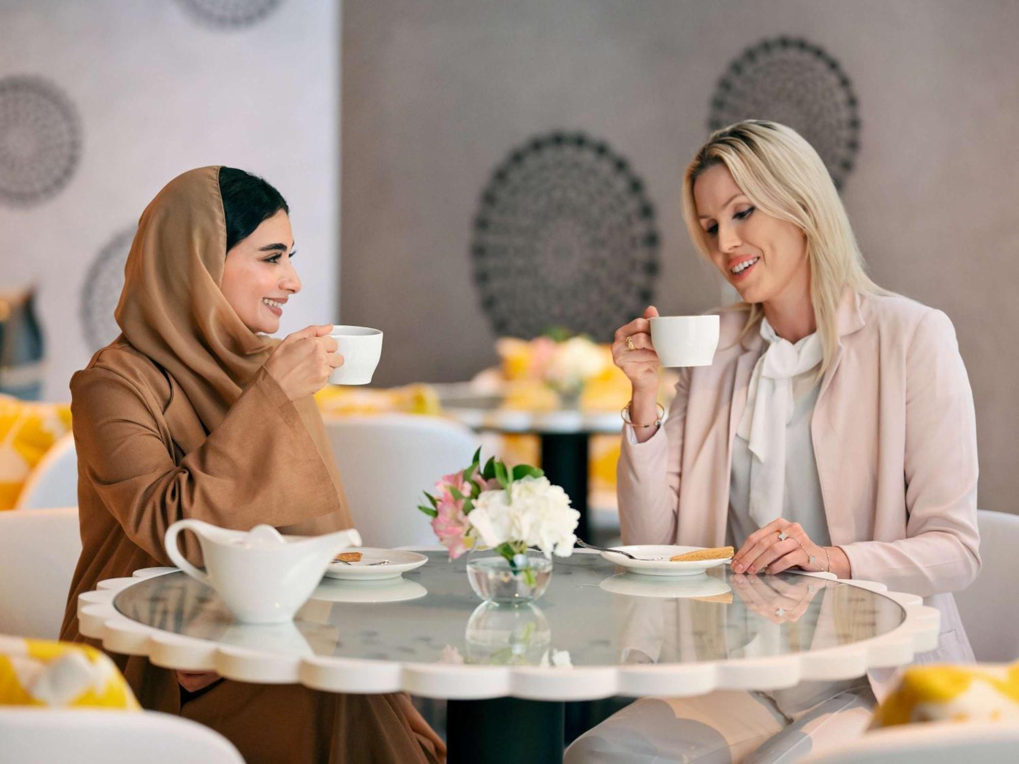 Moevenpick Hotel & Apartments Ghala Muskat Bagian luar foto Two women drinking coffee